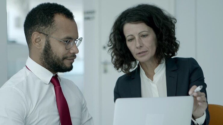Cheerful businessman and businesswoman using laptop