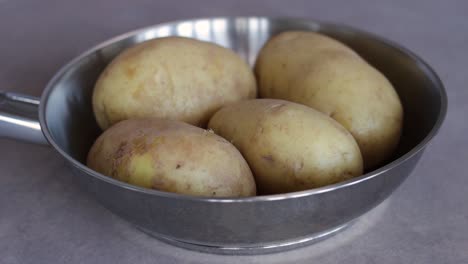 patatas frescas sin cocer con cáscara en un recipiente inoxidable