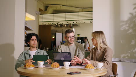 three colleagues discussing business over coffee in a cafe