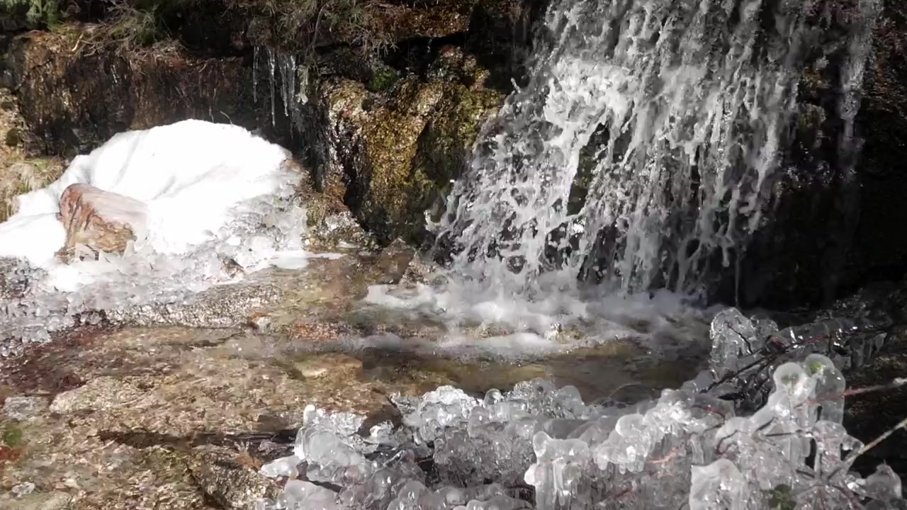 Et stort vandfald plasker ned i en sø omgivet af sne og is i Valle de la Fuenfría, Cercedilla