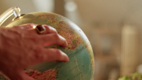 a hand with a ring touching a globe