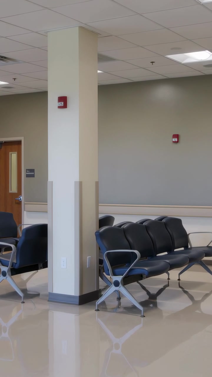 Video verticale: Telecamera in panoramica che documenta una colonna e sedie nere nell'area d'attesa di una clinica.