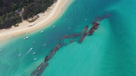 aerial: tangalooma shipwrecks beached in turquoise australia sea, moreton island