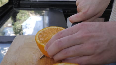 young male slices in orange in bright kitchen