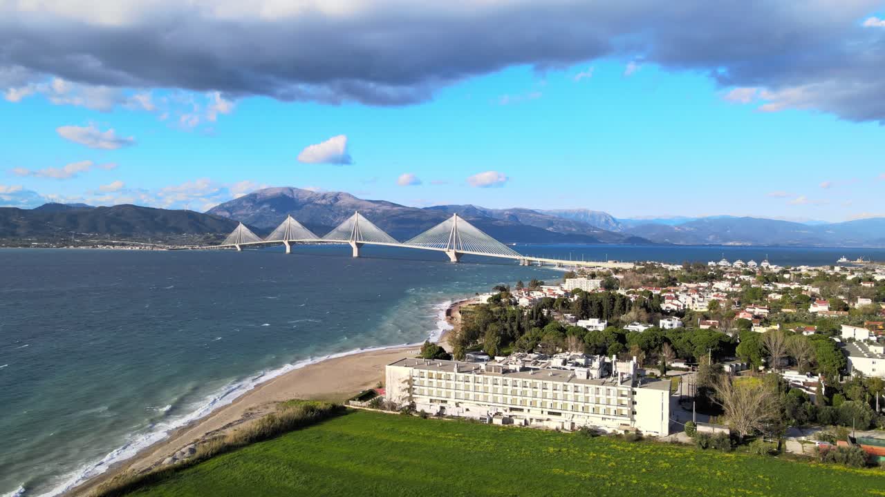 Vista aerea con drone del Ponte Rion Antirion con edificio di un hotel fronte mare e litorale a Patrasso, Grecia, in una giornata di sole