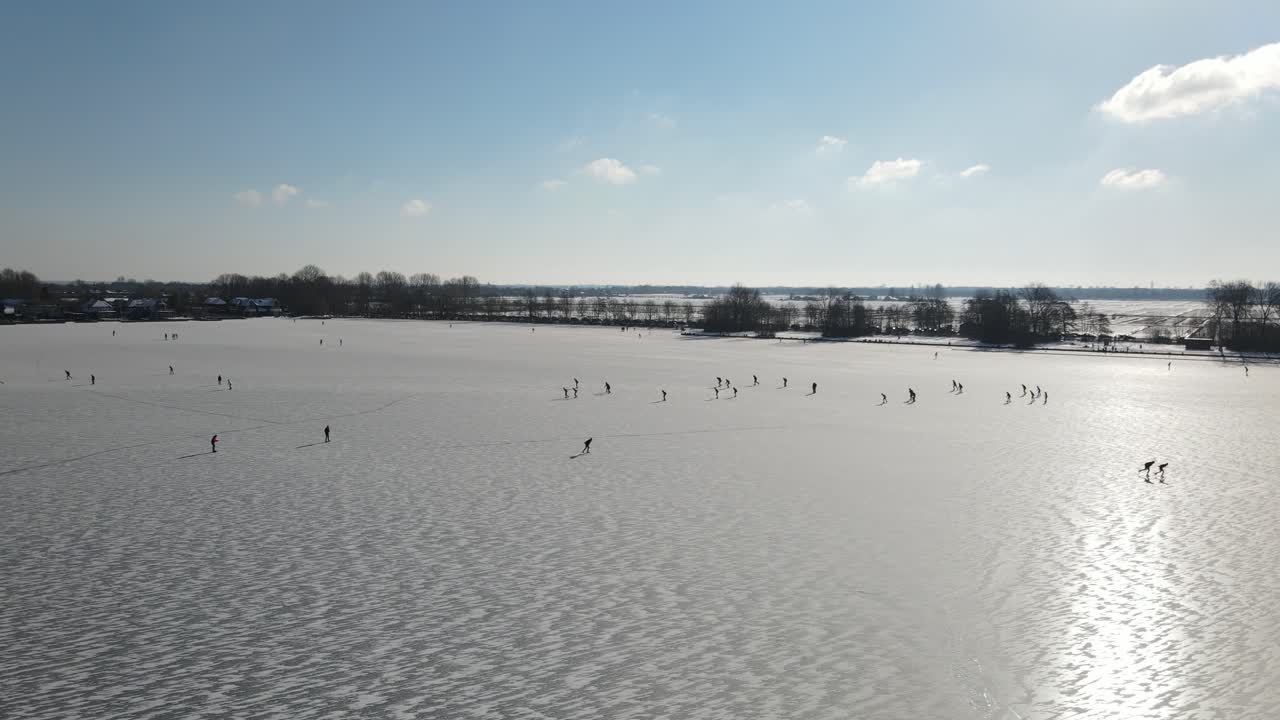 un dron aéreo disparó sobre un lago congelado durante el frío día de invierno con niños patinando sobre hielo durante la luz del sol