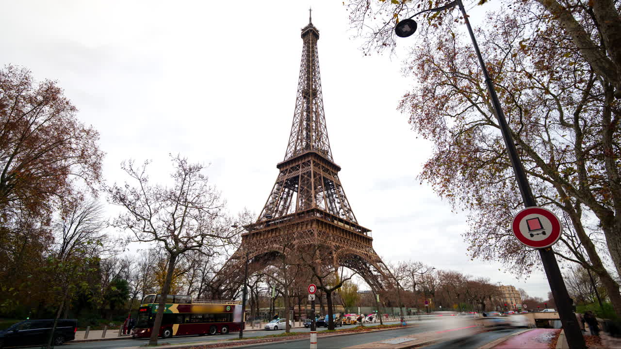 Torre Eiffel a Parigi in hyperlapse con foglie che cadono e traffico durante una giornata nuvolosa.