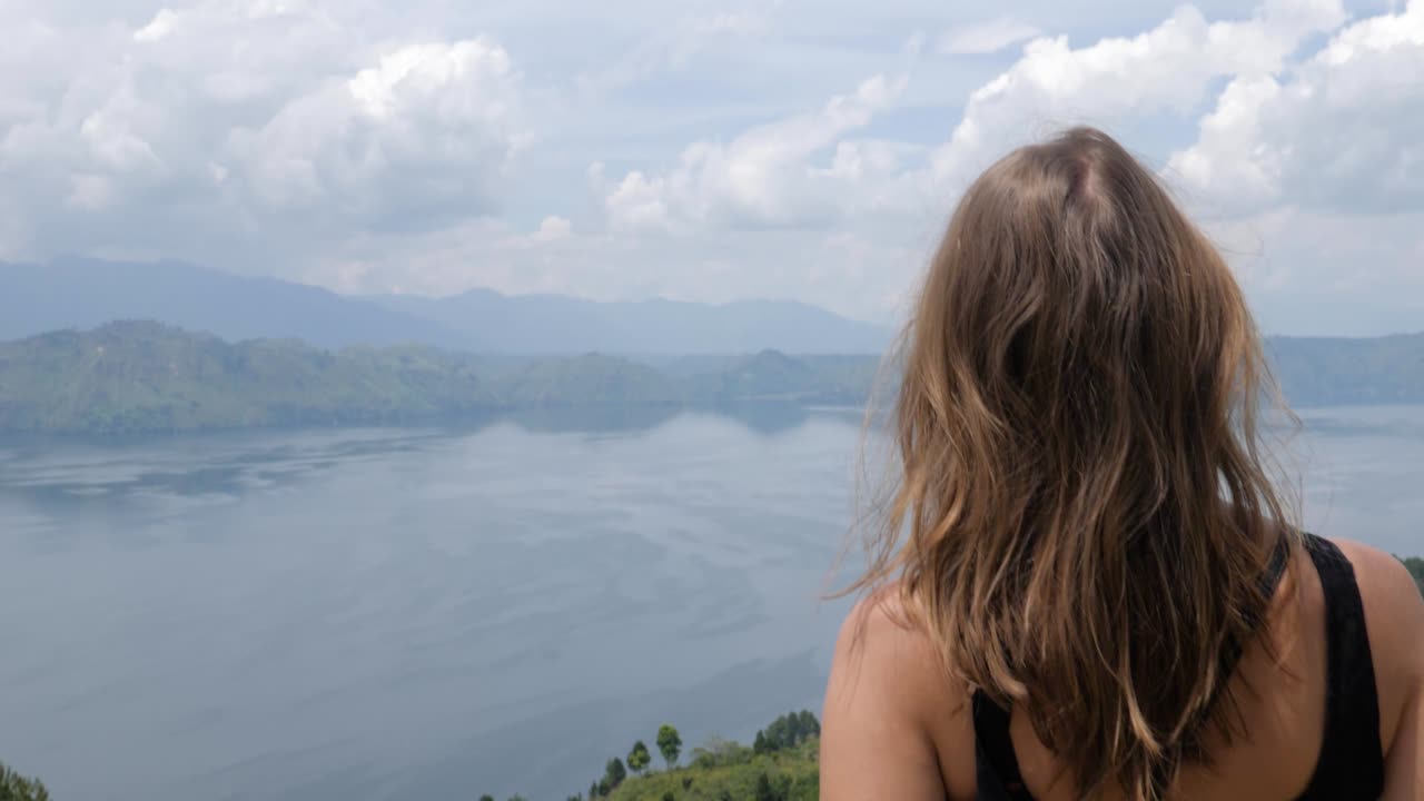 Ultra slow motion shot of young caucasian woman looking at Lake Toba from Samosir Island in North Sumatra, Indonesia