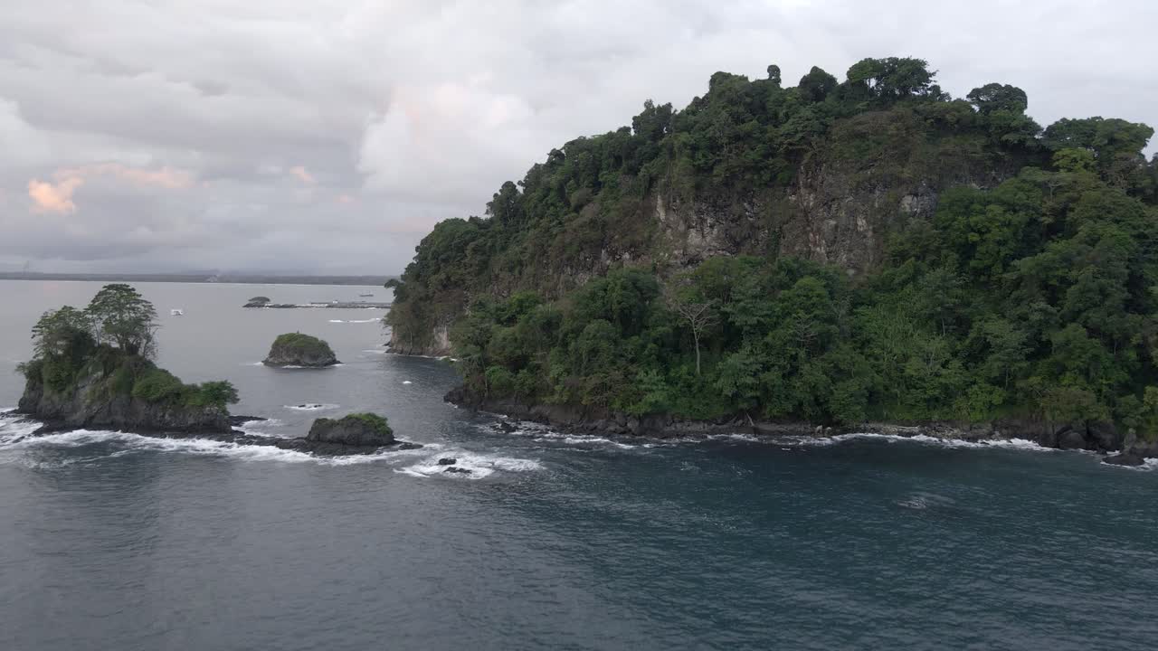Drone approaching a rugged and lush coast line at the south pacific