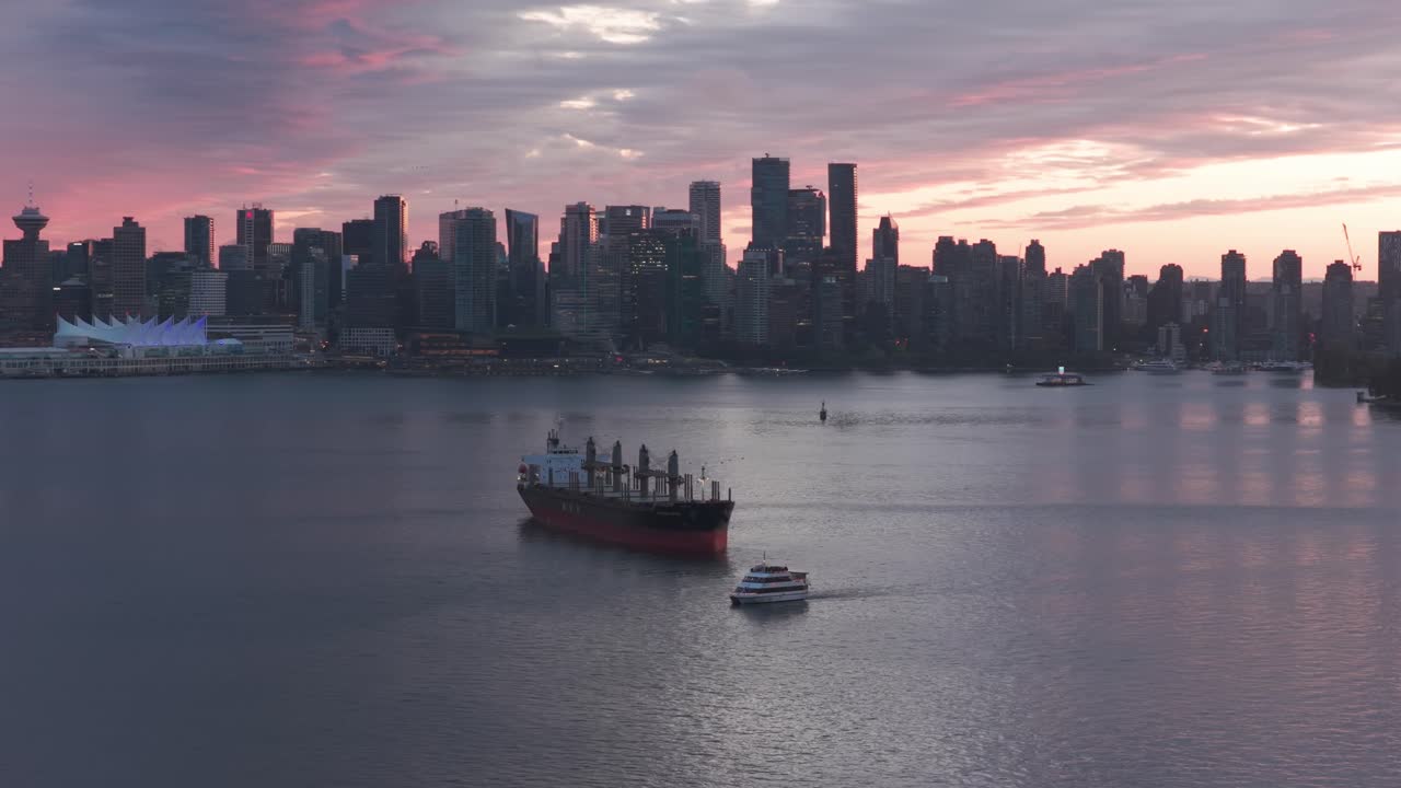 Telephoto wide panning aerial shot of a commercial vessel and seabus in the Port of Vancouver at magic hour in British Columbia, Canada. 4K