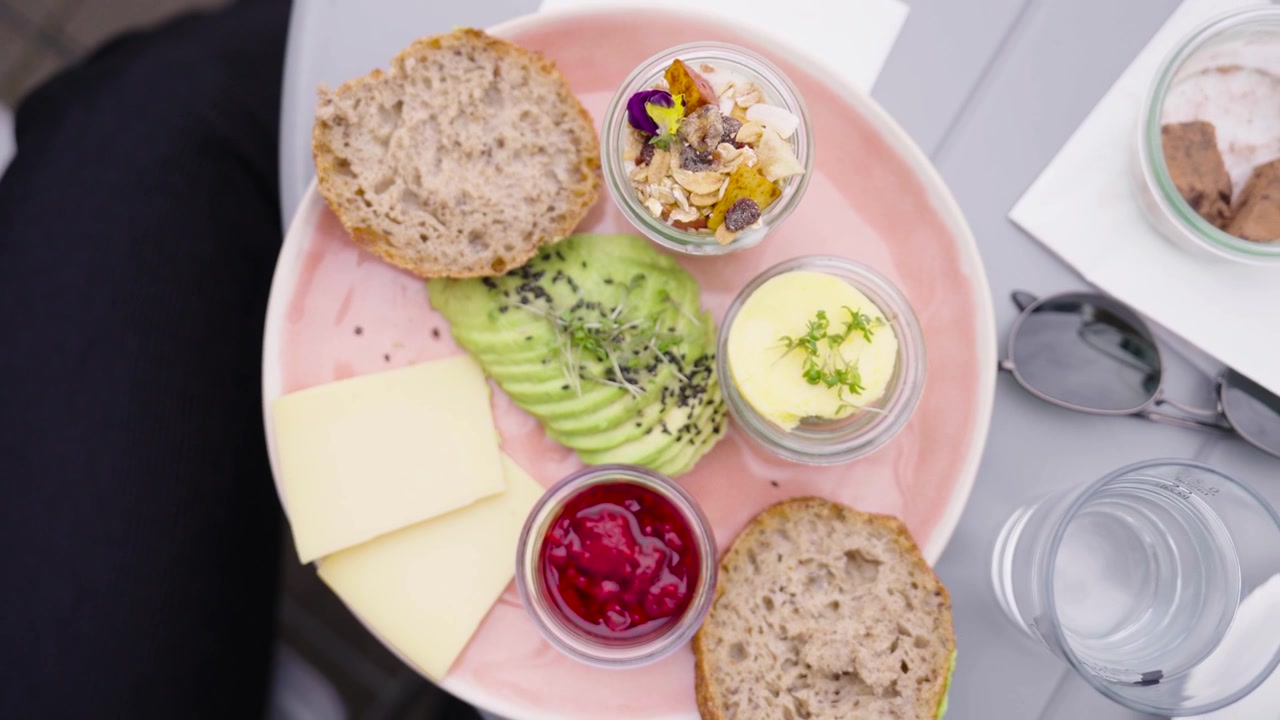 Ovenfra-perspektiv av en sunn vegetarisk snackstallerken, solbriller og vann.
