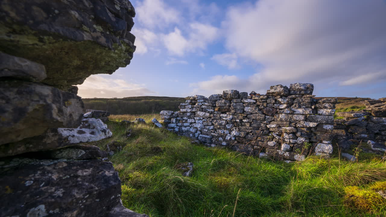 timelapse de la naturaleza rural tierras de cultivo con antiguas ruinas de casas abandonadas en primer plano en el campo de hierba durante un día soleado y nublado visto desde carrowkeel en el condado de sligo en irlanda