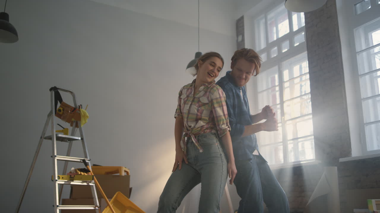Familia alegre disfrutando de arreglos en el hogar. Pareja feliz bailando dentro.