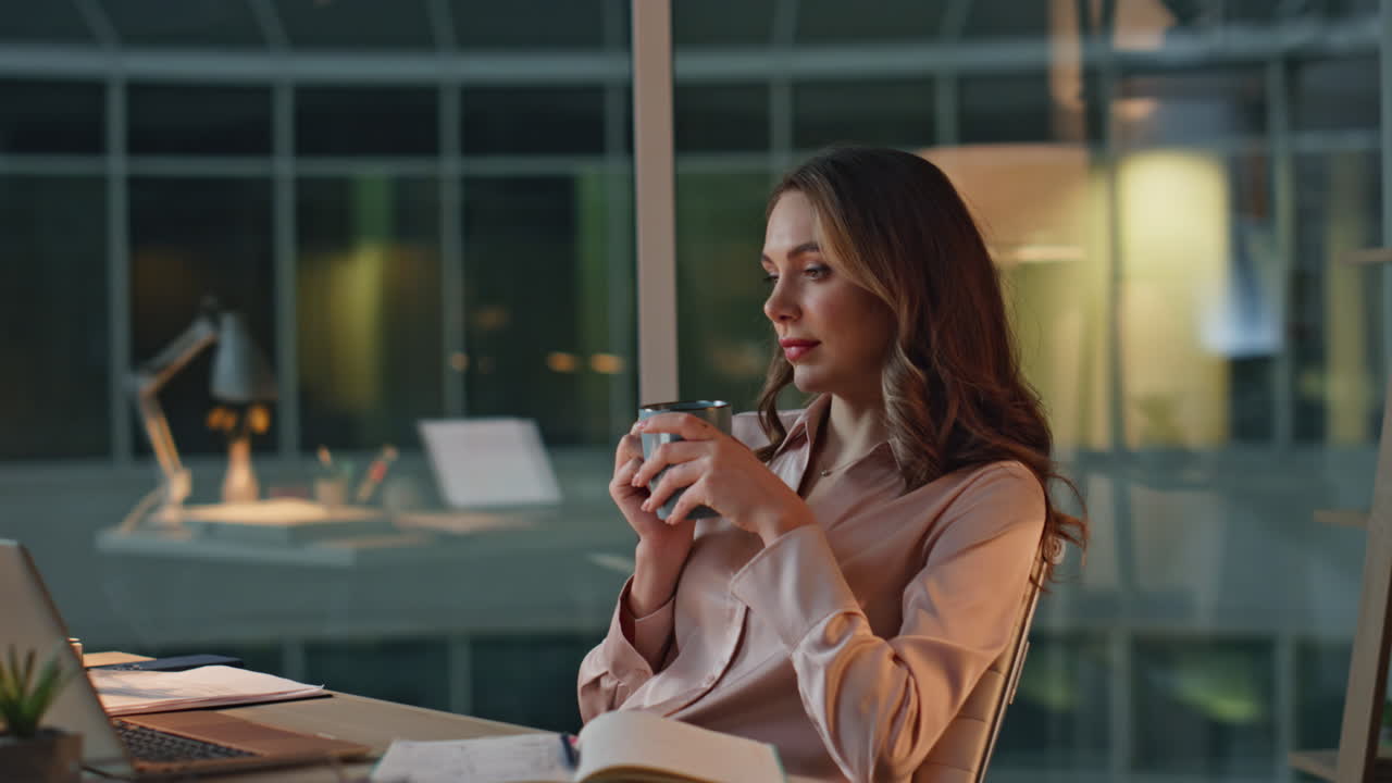 Iværksætter slapper af på kontoret om aftenen med kaffe. Tankefuld professionel holder pause.