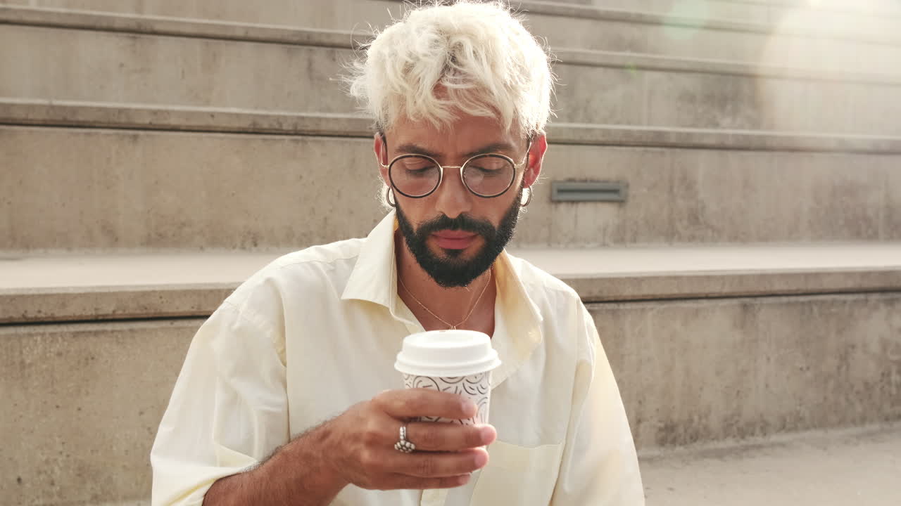 Young Man Sipping Coffee Outdoors on Concrete Steps