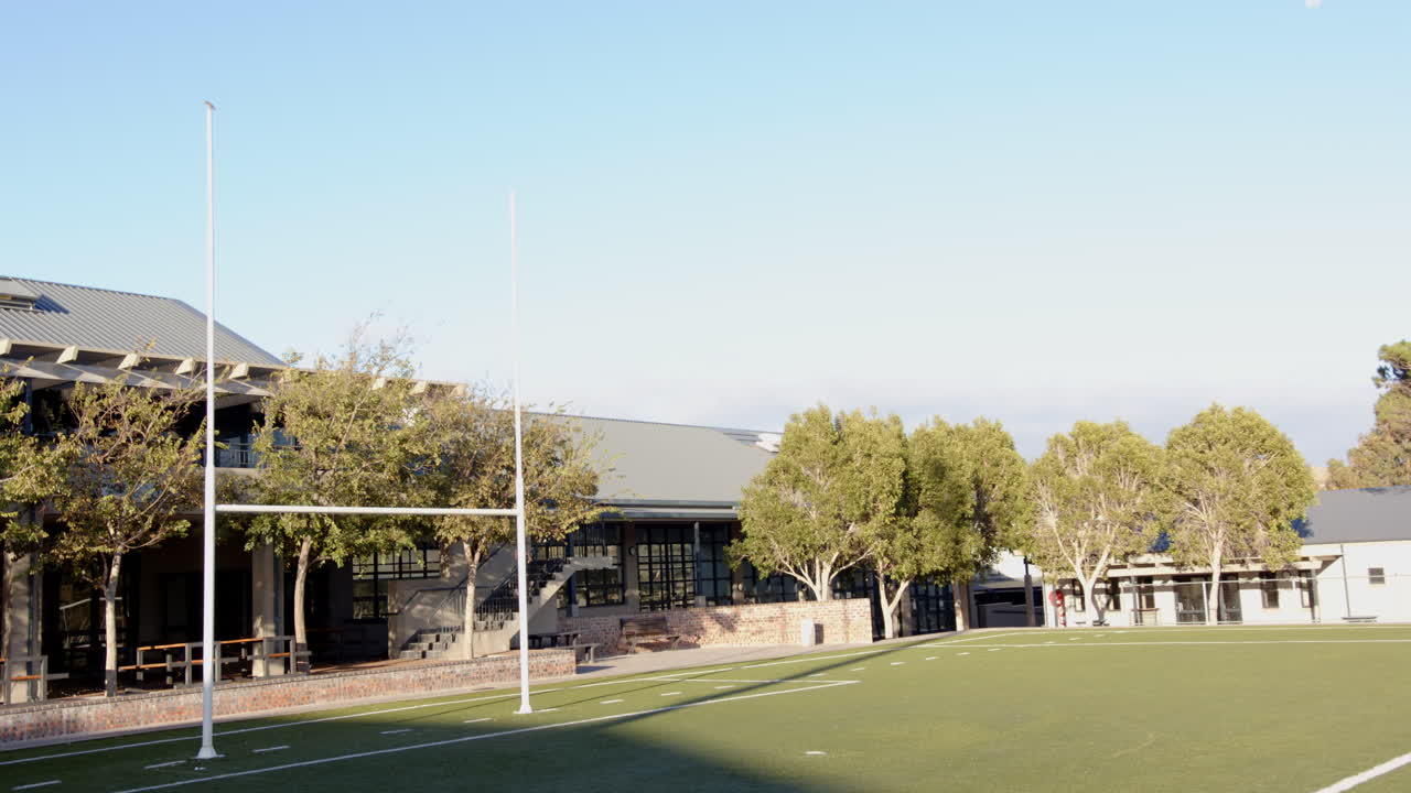 Football field with goalposts and trees, ready for school sports activities, copy space