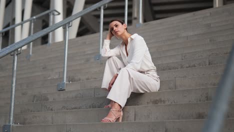 a businesswoman sits on the steps in front of a modern building