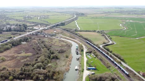 Aerial-drone-shot-of-train-running-along-the-River-Stour-in-Kent,-England