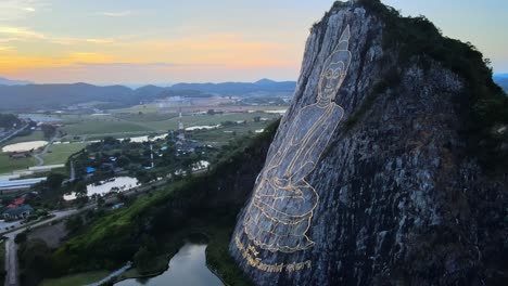 imágenes de drones de 4k que rodean una imagen de buda, sentado con las piernas cruzadas, grabado con oro en la cara norte de una colina de piedra caliza en khao chi chan, tailandia