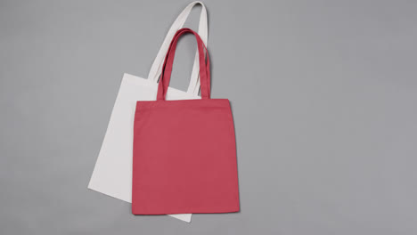 Primer-Plano-De-Bolsas-Blancas-Y-Rojas-Sobre-Fondo-Gris,-Con-Espacio-Para-Copiar,-Cámara-Lenta