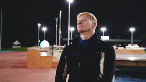 sportive blond man doing stretching exercises before training in the park at night 3