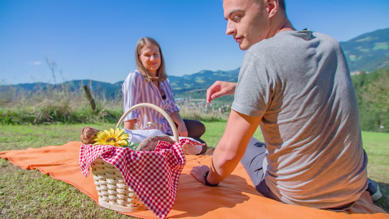 Young romantic boy takes sunflower from basket and gives it to his sexy girlfriend on summer day