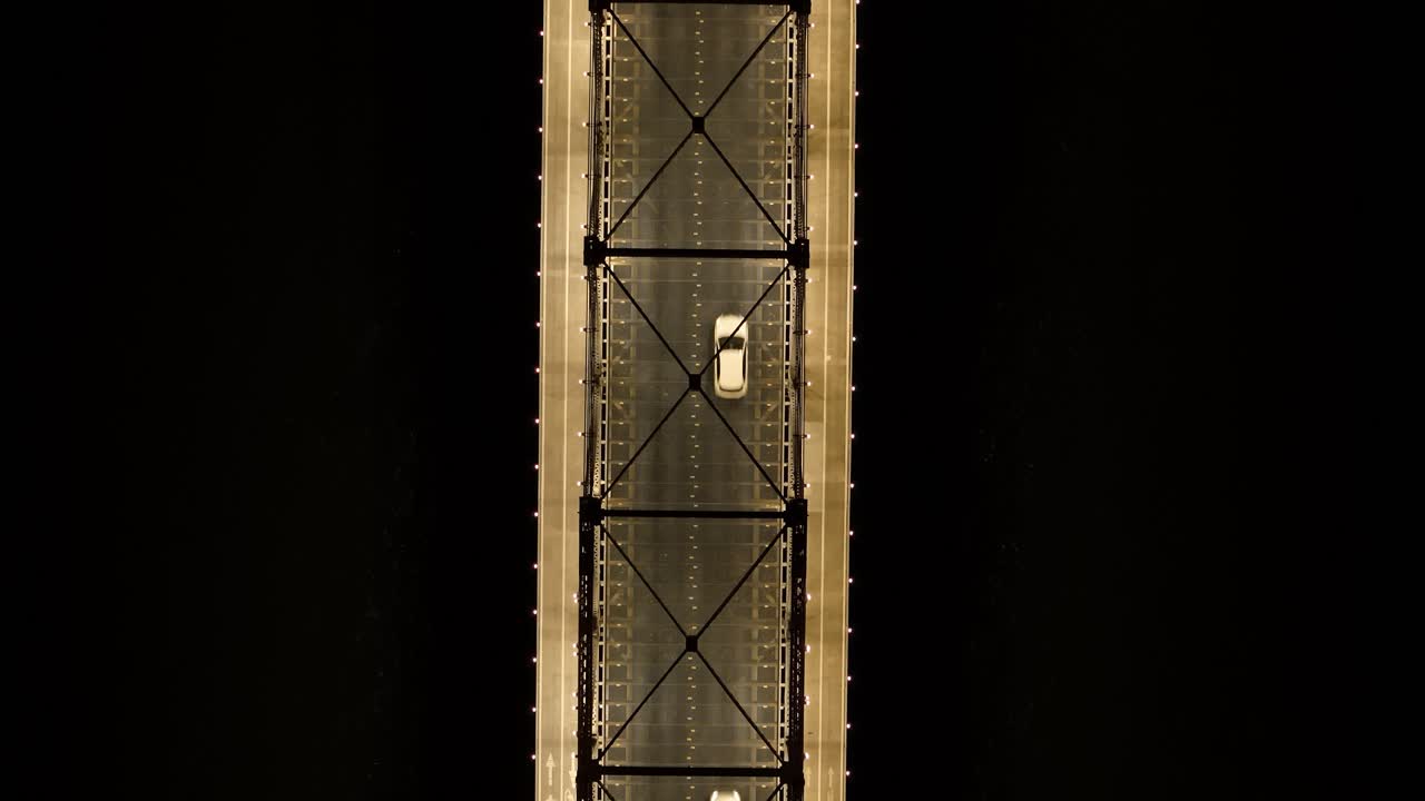 Primo piano da drone dei cavi d'acciaio e delle torri del Ponte Hercilio Luz che brillano di notte. Architettura industriale dettagliata