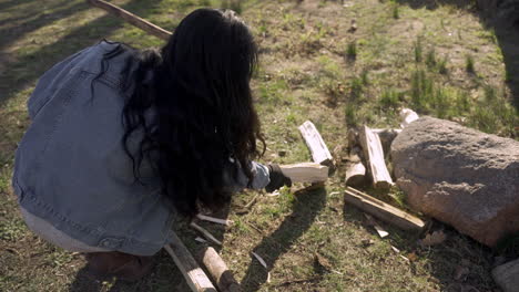 caucasian woman picking up firewood outside a country house