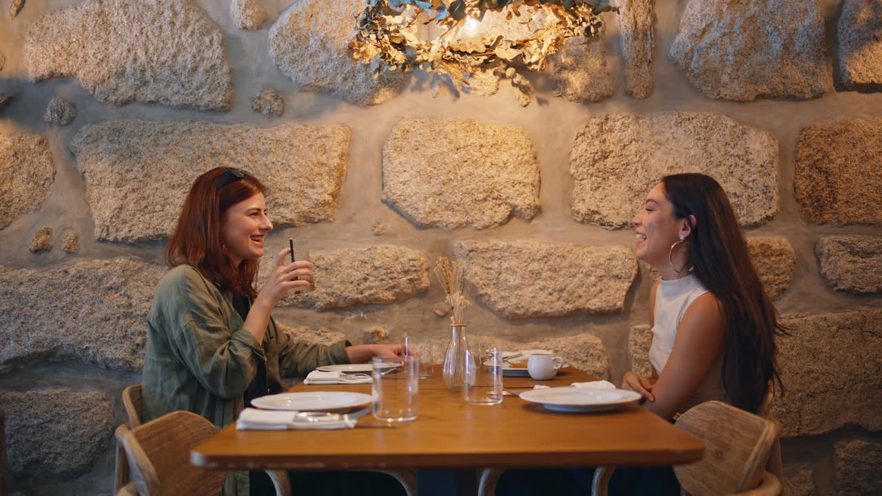 두 여자 가 편안 한 식당 에서 식사를 즐기고 있다