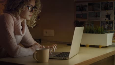 side view of woman in front of laptop at home to late