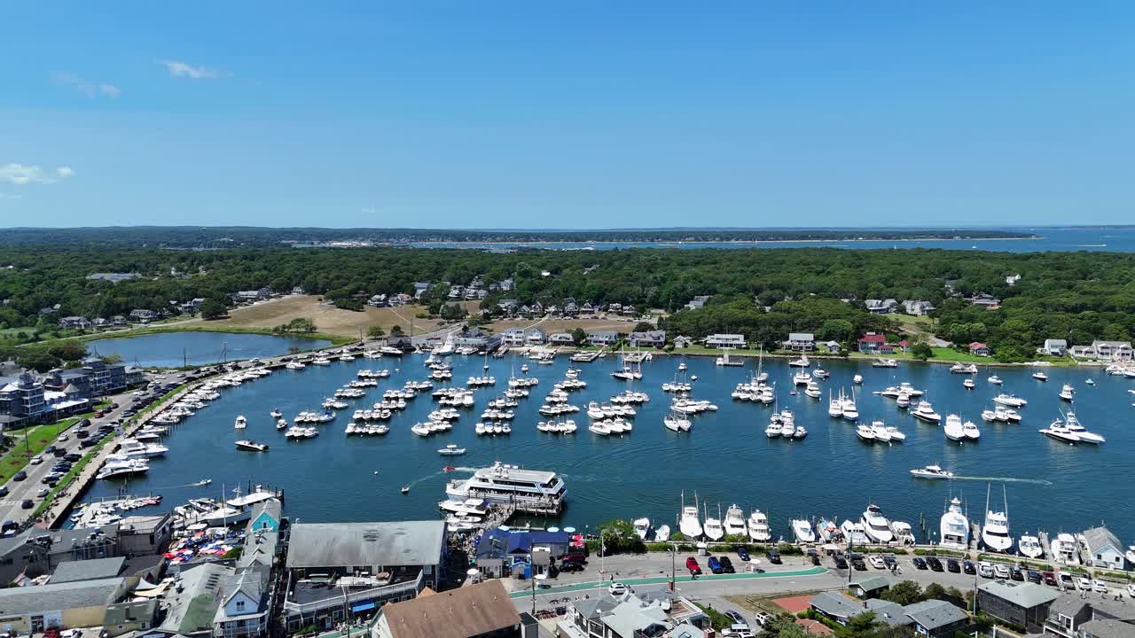 Veduta aerea con drone del porto di Martha's Vineyard nella Contea di Dukes, Massachusetts, con un porto turistico pieno di barche, case costiere e vegetazione rigogliosa lungo la pittoresca costa insulare del New England. Ripresa laterale.