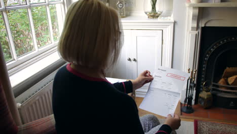 an unrecognizable senior woman worried about debts opening a debt letter