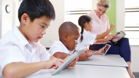 School-kids-and-teacher-using-digital-tablet-in-classroom