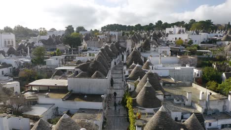 Beautiful-Aerial-View-of-Tourists-Walking-on-Quiet-Streets-of-Alberobello,-Apulia,-Italy