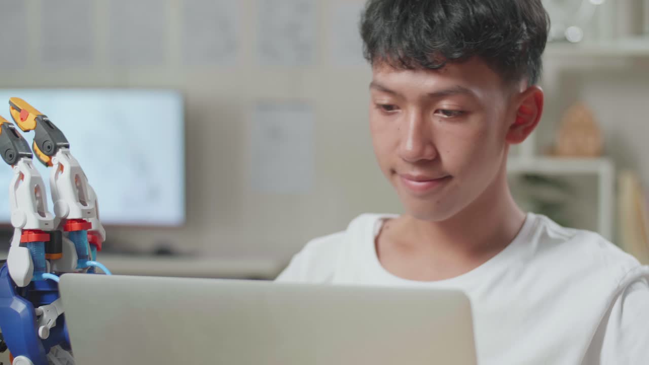 아시안 소년이 성공을 축하하는 클로즈업: 집에서 노트북을 사용하는 사이보그에 대한 작업