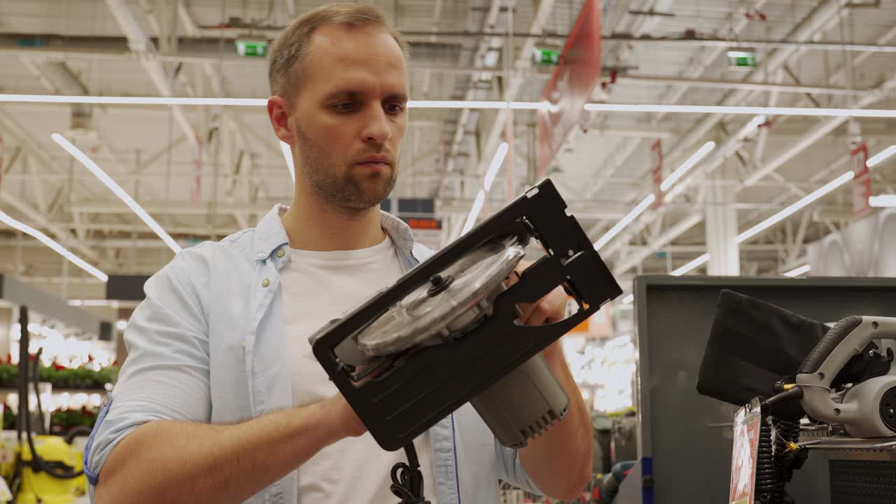 Man chooses a circular saw in a tool shop. Male select a product in a hardware store