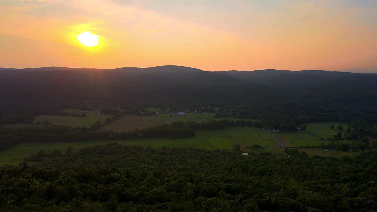 Aerial drone video footage of a golden hour summer sunset in a green, vibrant rural Appalachian Mountain valley with beautiful light. In particular, this is in New York's Hudson Valley