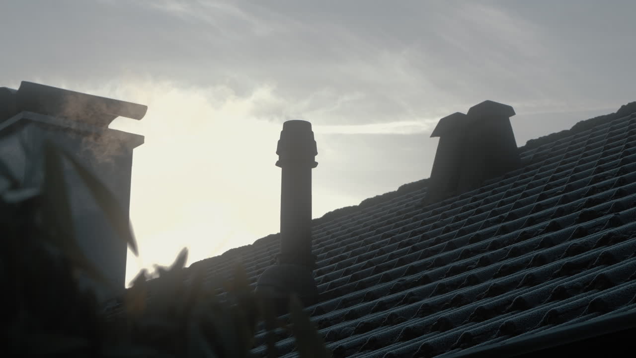 Steam smoke from a chimney in the winter frozen roof of house. Sun in the background. 4K Slow Motion. Early in the Morning. Sunrise