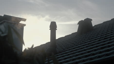 steam smoke from a chimney in the winter frozen roof of house. sun in the background. 4k slow motion. early in the morning. sunrise