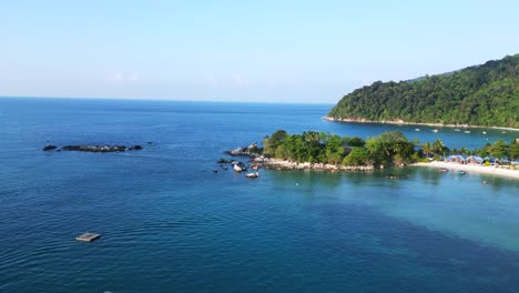 Spectacular-aerial-view-flight-of-a-Hut-on-a-tropical-Sole-peninsula-with-turquoise-water-and-lush-green-vegetation