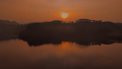 Beautiful-landscape-with-high-rocks-with-illuminated-peaks,-stones-in-mountain-lake,-reflection,-blue-sky-and-yellow-sunlight-in-sunrise-in-kerala,-india