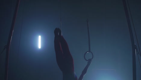 gymnast performing gymnastic cross exercise on gymnastic rings. shot in slow motion.