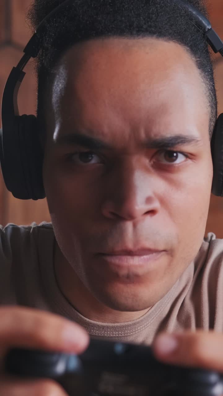 Giovane uomo afroamericano con cuffie che inizia un videogioco con il gamepad