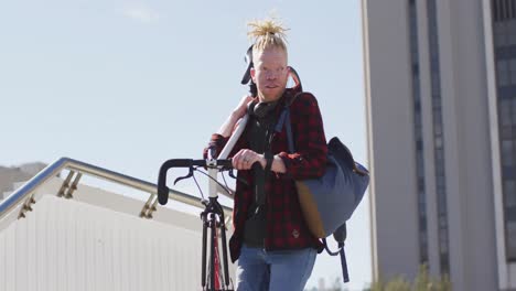 bedachtzame albino afrikaans-amerikaanse man met dreadlocks die trappen af gaat met de fiets