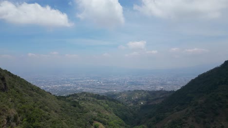 Drone-Dolly-Shot-Pulling-Away-from-View-of-San-Jose-Costa-Rica-seen-Between-Mountains