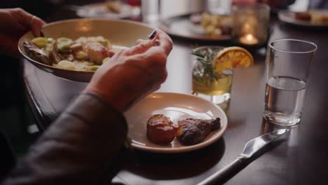 person at restaurant placing shared food on plate