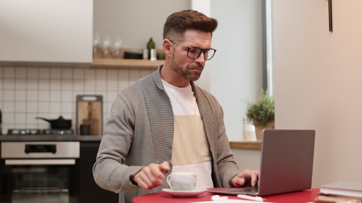 Man Drinking Coffee and Using Laptop