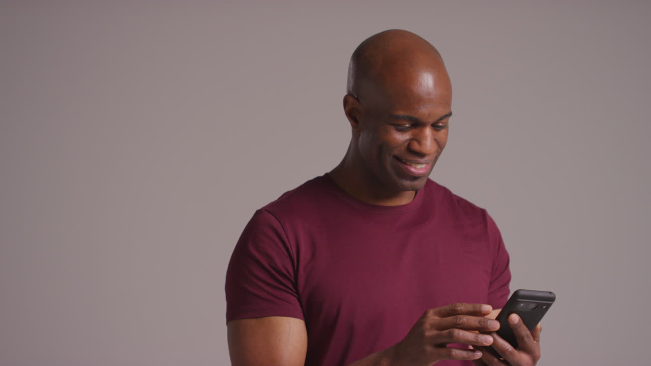 Studio Shot Of Smiling Mature Man With Mobile Phone Getting Good News Against Grey Background 3