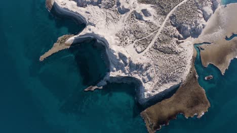 vista aérea escénica del magnífico paisaje patagónico rodeado por el mar azul turquesa en península valdés, costa argentina - toma en órbita a cámara lenta, de arriba hacia abajo