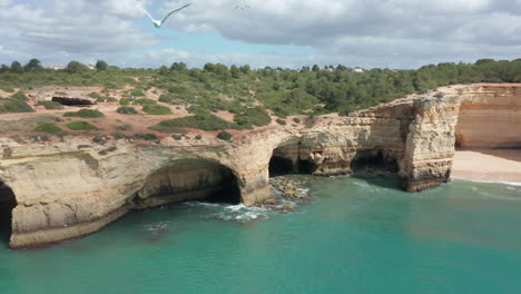 Drone-pulling-away-from-beautiful-shoreline-with-caves-and-cliffs